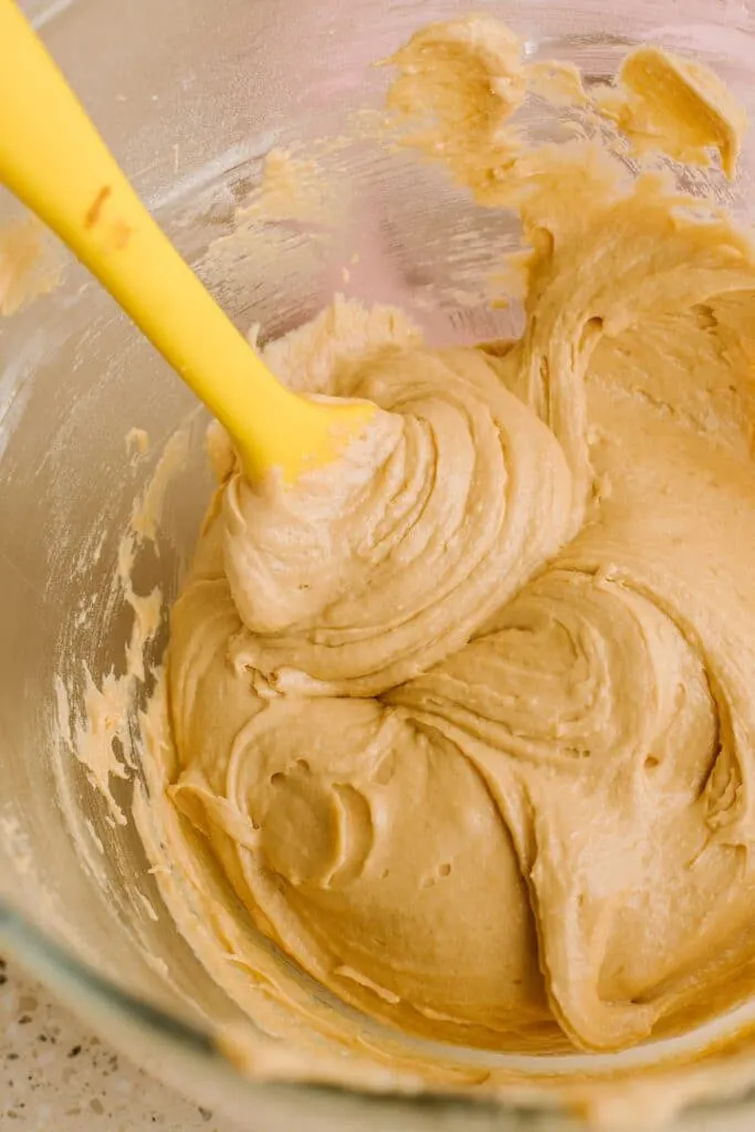 speculoos cupcake batter in glass bowl with yellow spatula