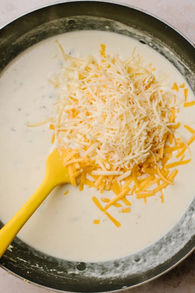 shredded parmesan and cheddar cheese with half and half in skillet