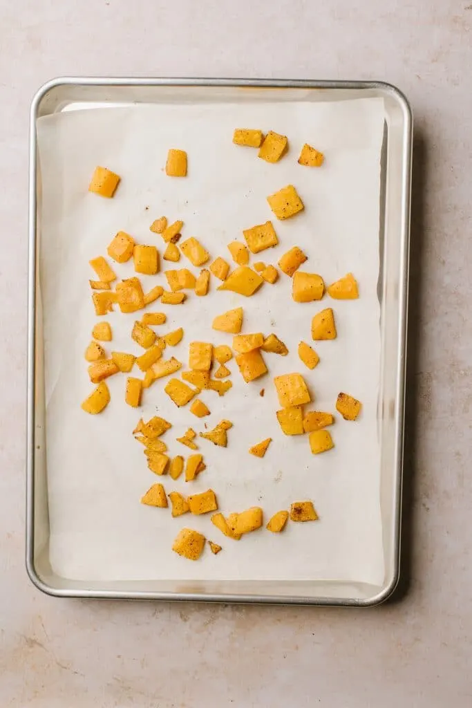 cubed butternut squash on parchment lined baking sheet