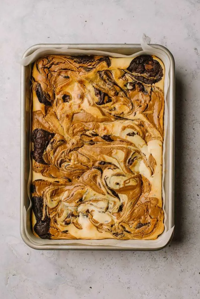 baked and fudgy swirled cookie butter cheesecake brownies in baking dish