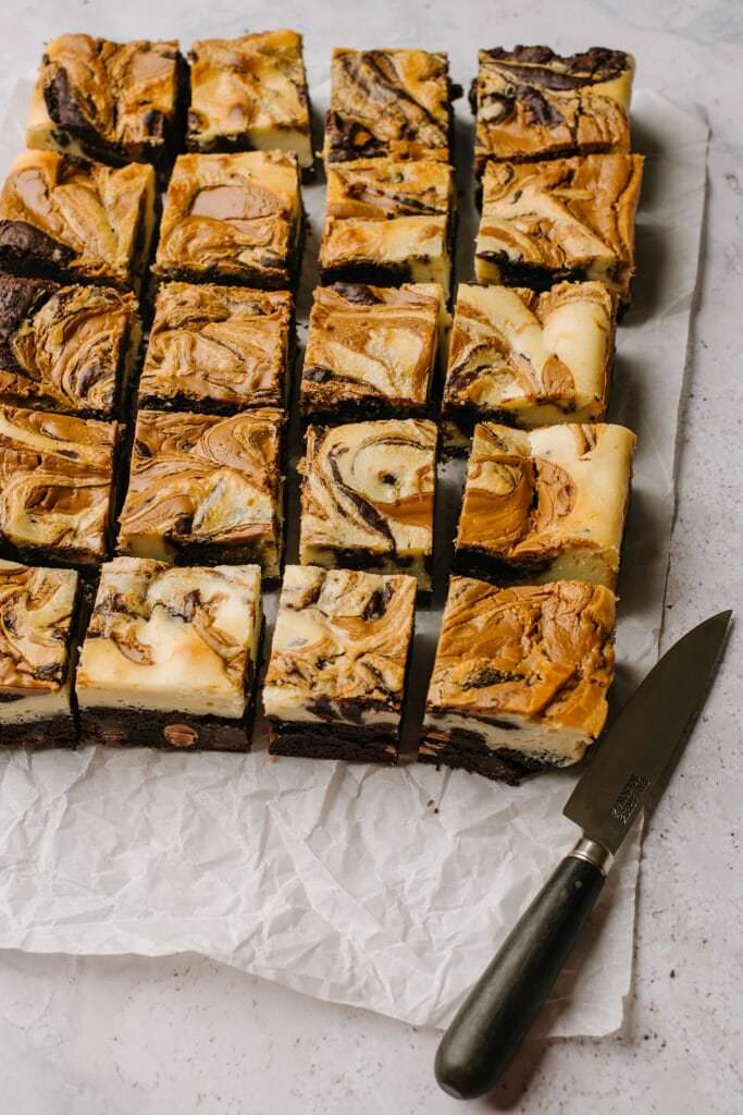 cream cheese brownie bites on parchment paper with knife