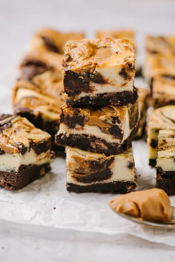 stack of three cheesecake brownies with biscoff spread and squares of brownies