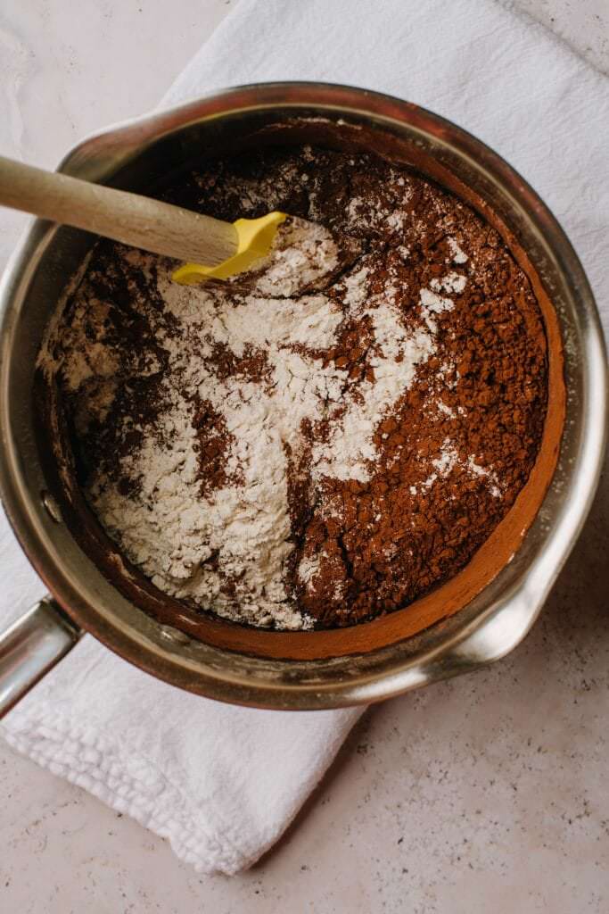 flour and cocoa powder with melted butter and sugar in saucepan