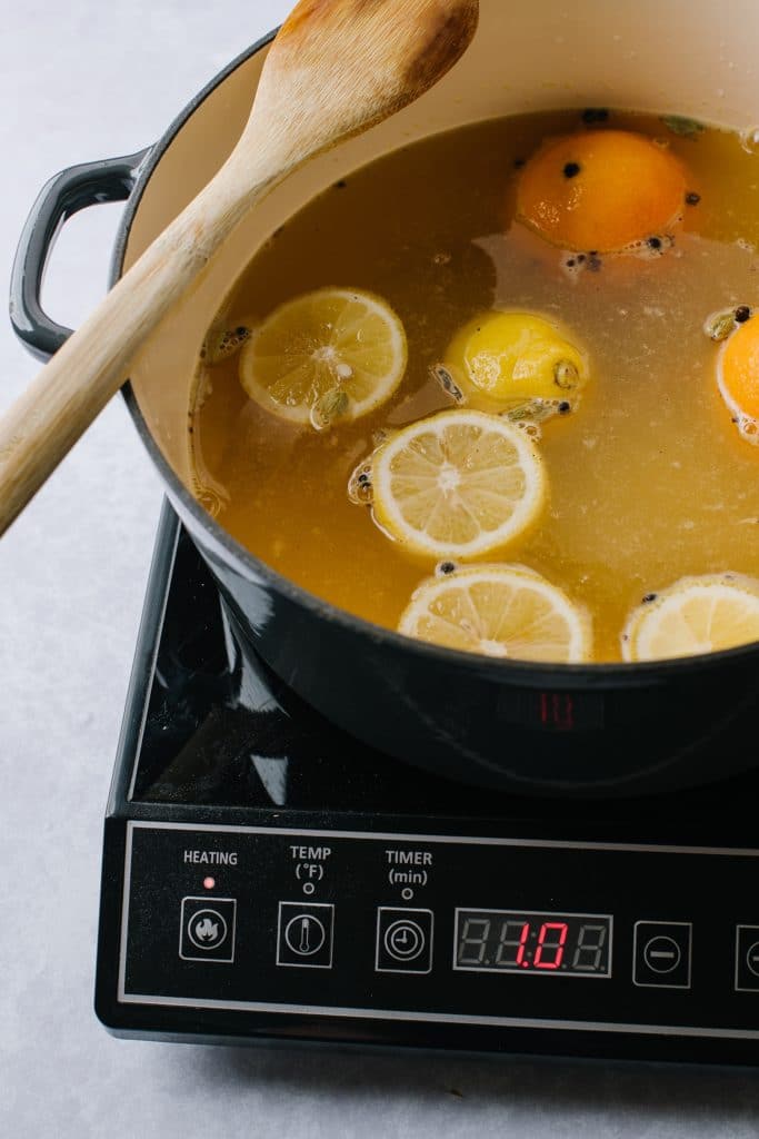 simmering pot of german mulled wine with fresh citrus slices and cloves