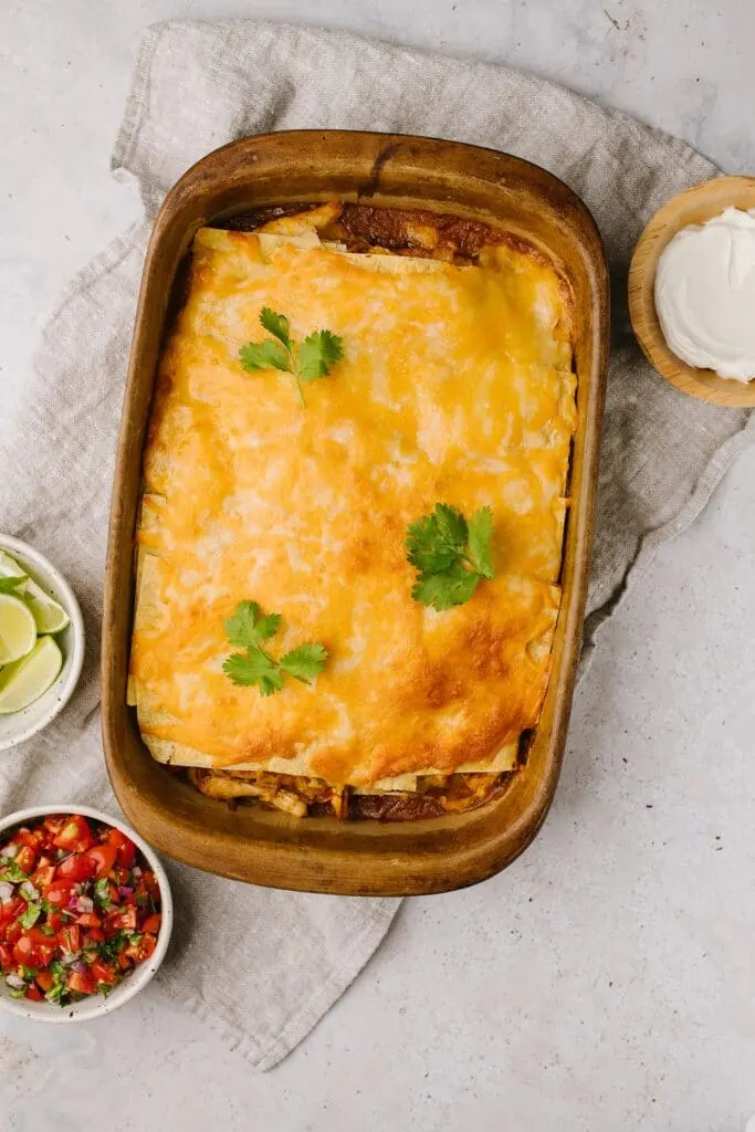 cheesy chicken and corn tortilla casserole in baking pan garnished with cilantro