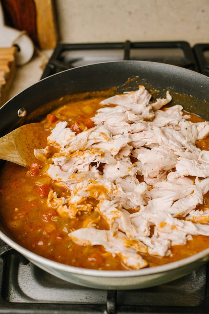 shredded chicken with tomato onion stock in skillet
