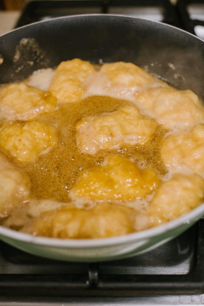 dumplings simmering in maple syrup sauce in skillet