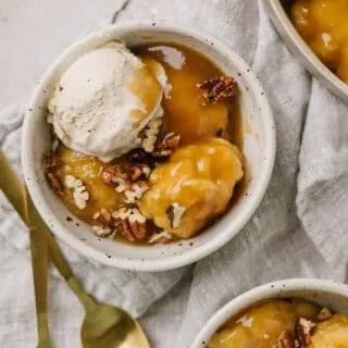 maple dumplings topped with vanilla ice cream in two small white bowls with gold spoons