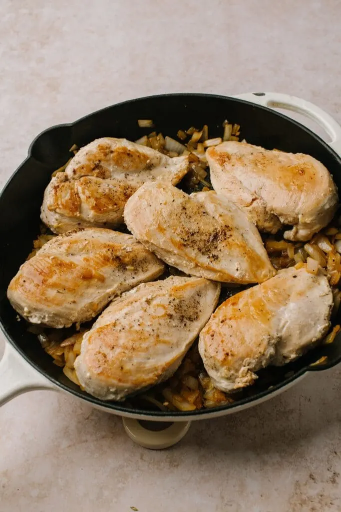 seared chicken breasts and onions in cast iron skillet