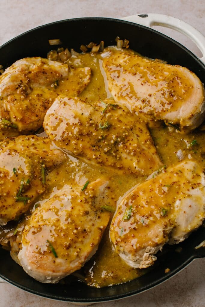 chicken and onions topped with honey mustard sauce in cast iron skillet