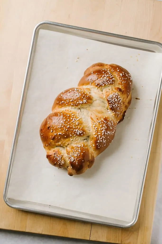 braided cardamom bread on parchment lined baking sheet