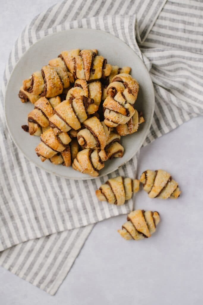 A plate of fresh chocolate cinnamon rugelachs in crescent shapes.