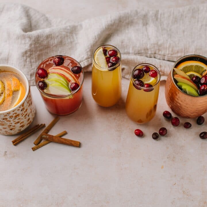 A shot with the multiple variations of spiced apple cider cocktails, both warm and chilled, with various types of garnishes and alcohol.
