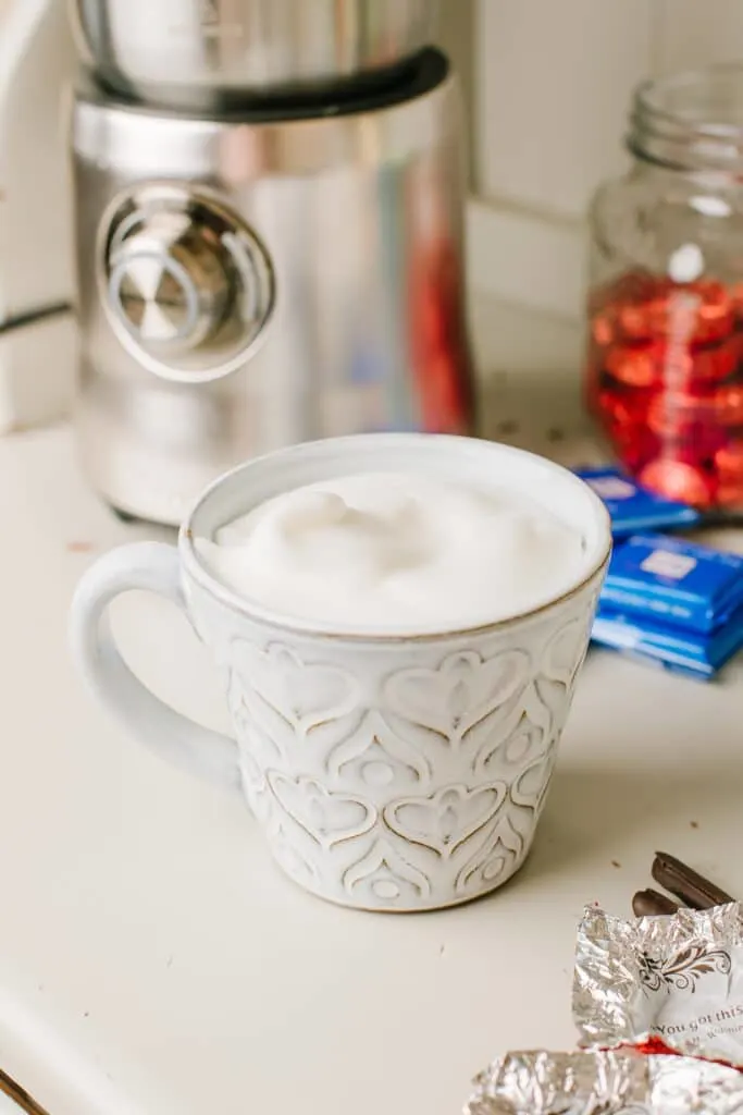 A mug of steamed hot chocolate, topped with frothed milk.