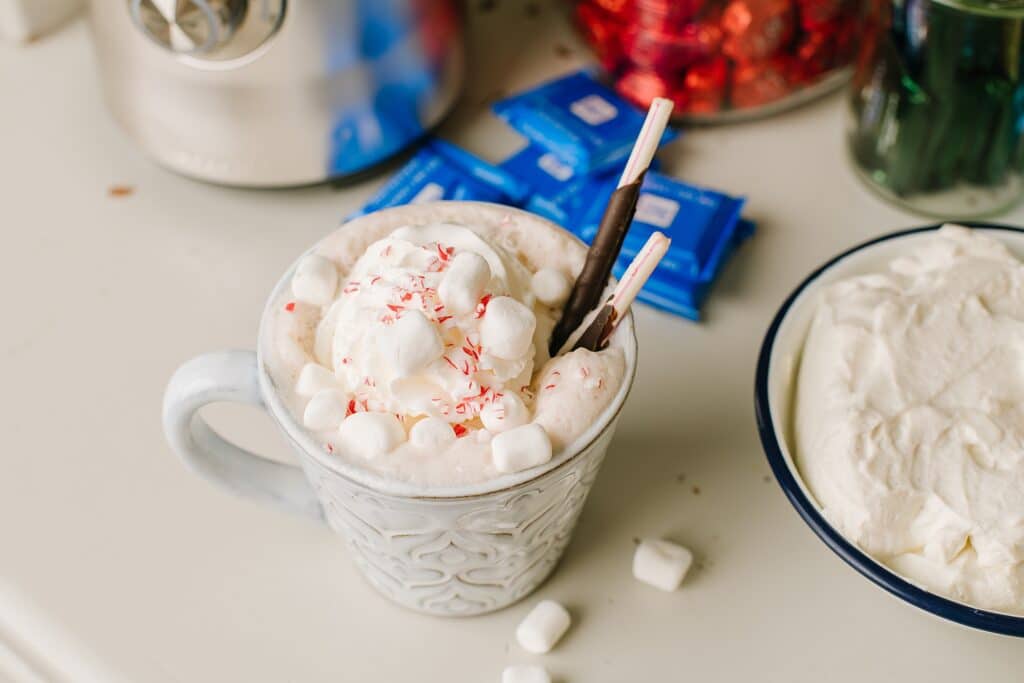 A mug of steamed hot chocolate, piled high with marshmallows and peppermint candy.