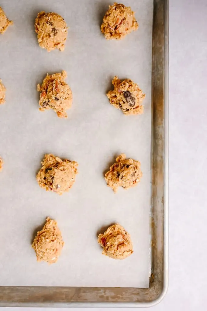 balls of Salted Peanut Butter Pretzel Cowboy Cookies dough on a sheet pan lined with parchment waiting to be baked