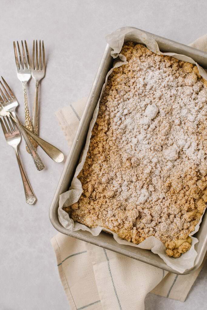 sheet pan of baked crumb cake with powdered sugar and forks next to it