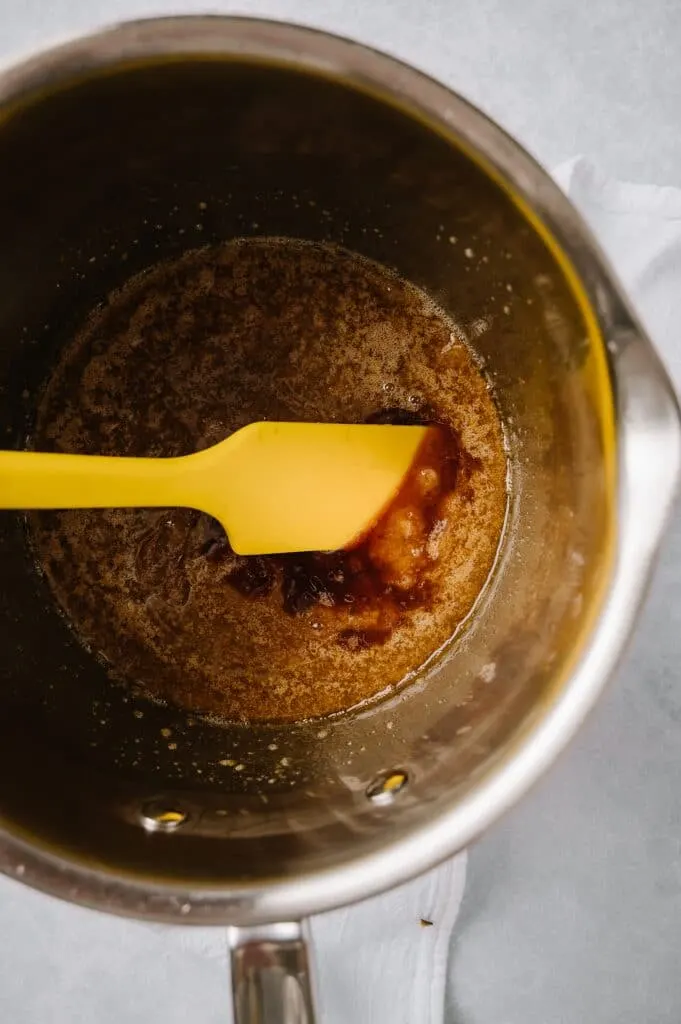 toffee in a saucepan with vanilla being stirred with a yellow spatula