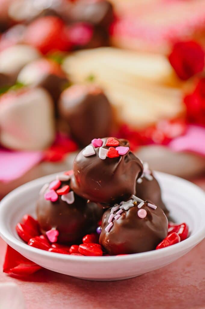 peanut butter balls in a dish with a valentines' day inspired cheesebaord in the background
