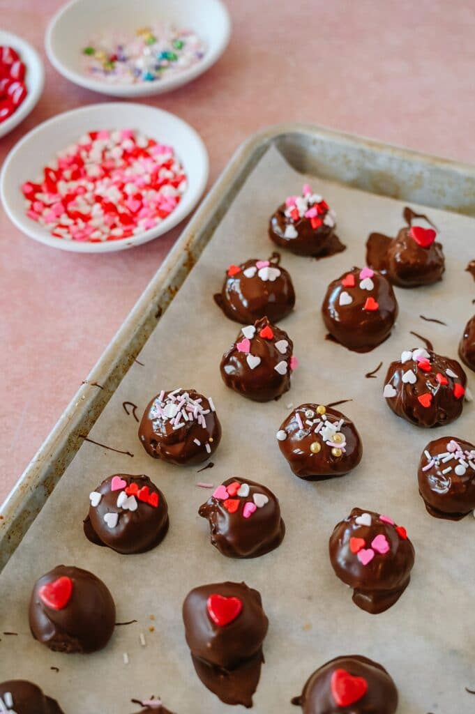sprinkles on peanut butter balls on a baking sheet setting up