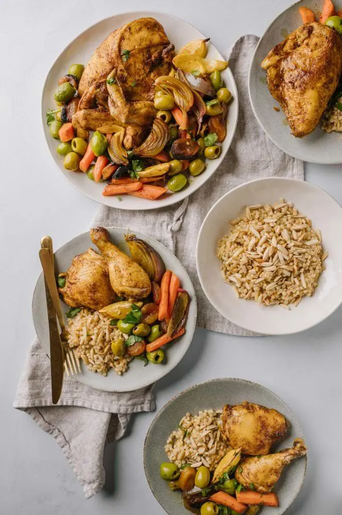 meal of Sheet Pan Moroccan Chicken with Olives and Apricots and Israeli couscous with toasted almonds on a table