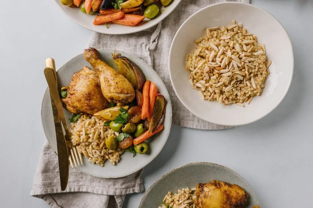 sheet pan chicken and vegetables next to a bowl of couscous