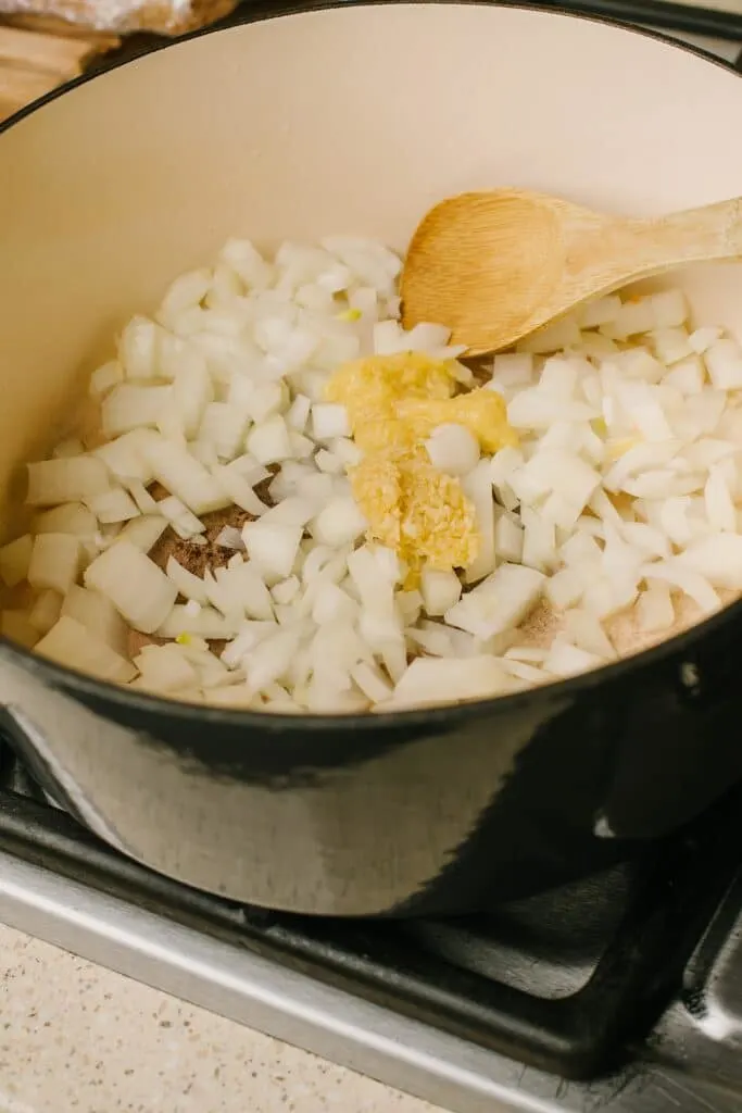 diced onions and other ingredients for chicken satay soup in a pot