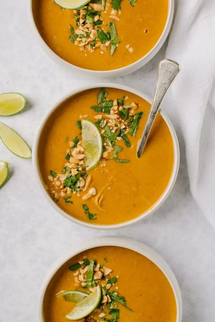 bowls of chicken satay soup with limes