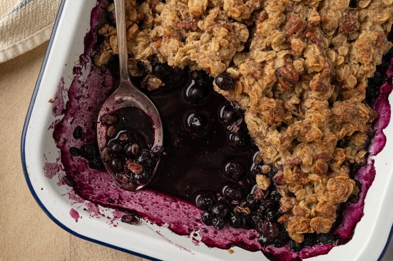 close up of gluten free blueberry crisp in a dish with a portion missing