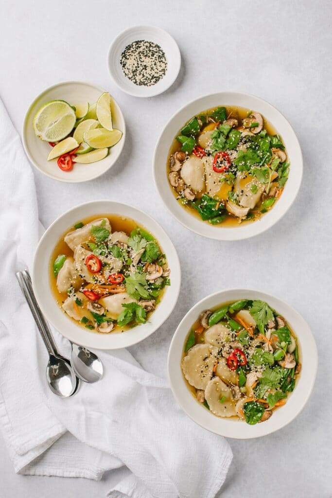 bowls of asian chicken soup with dumplings