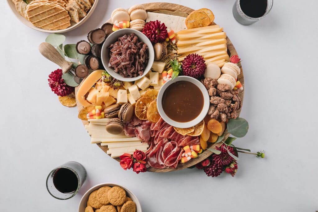 sweet and savory fall cheeseboard with crackers and glasses of red wine