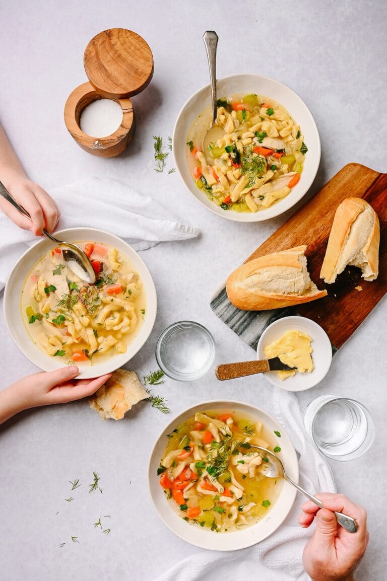 bowls of chicken soup with homemade noodles and bread